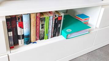 Eine weiße Unterhaltungsanlage mit Fernseher obenauf und einem Bücherregal darunter.