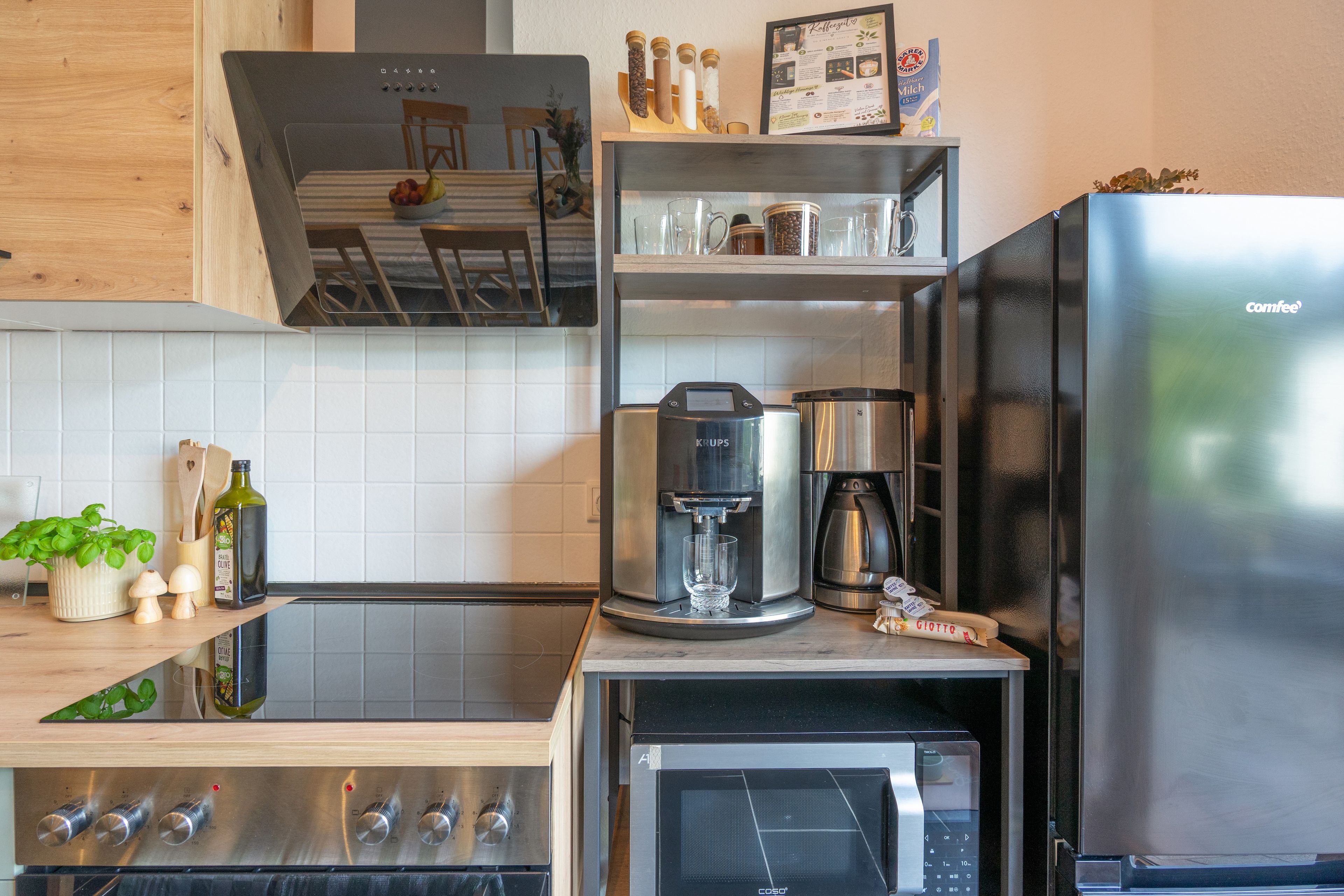 Een moderne keuken met een ingebouwde koffiezetapparaat, een magnetron en een roestvrijstalen koelkast.
