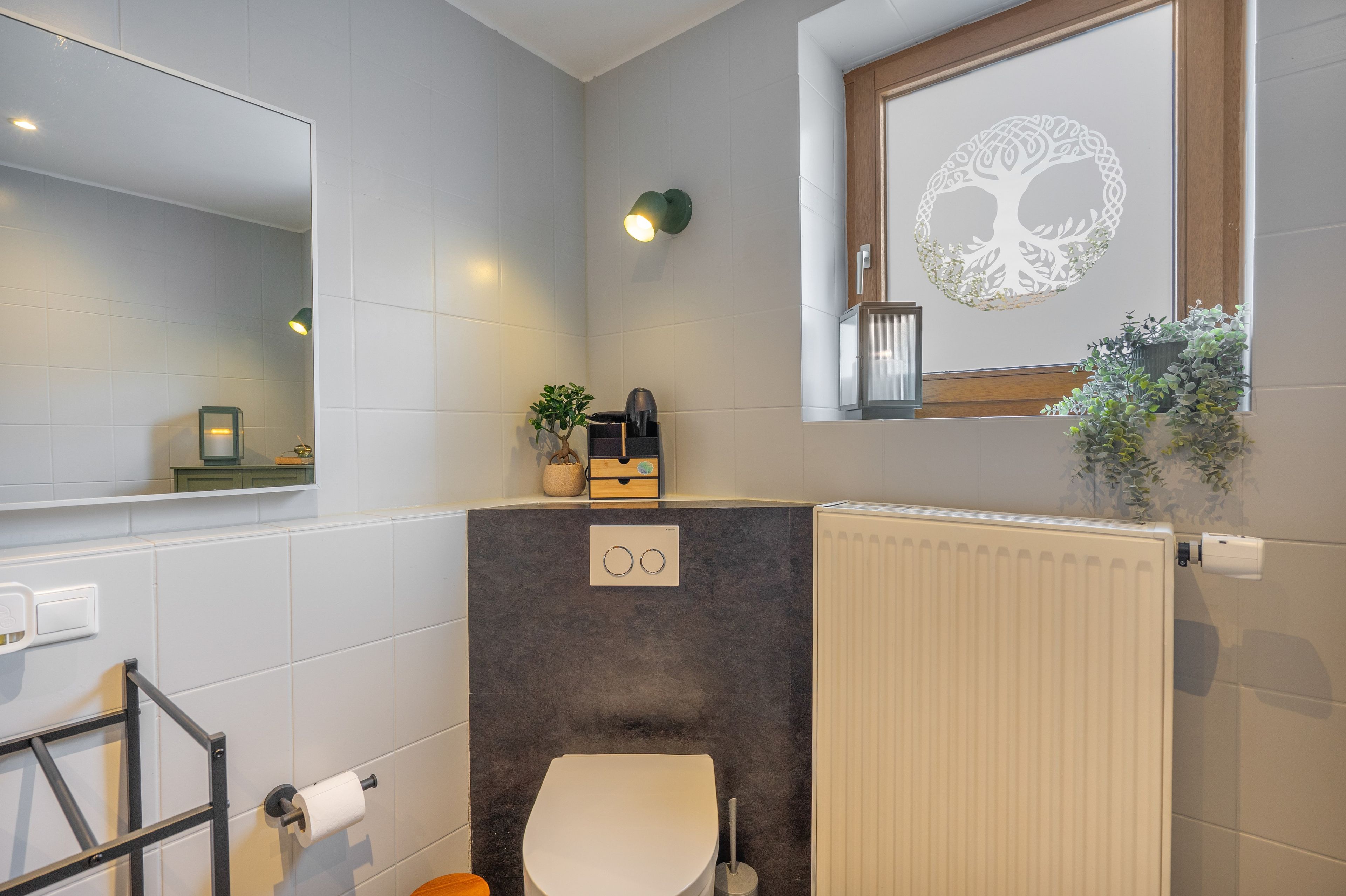 Ein Badezimmer mit Toilette, Handtuchhalter, Heizkörper und Spiegel.