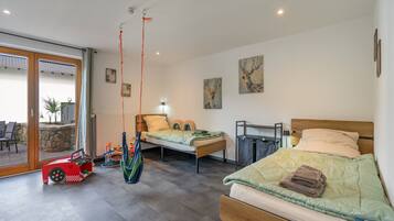 Ein modernes Schlafzimmer mit zwei Betten, einem Hängesessel und einem roten Spielzeugauto.