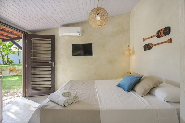 Quarto com cama, televisão, porta e prancha de remo fixada na parede.
