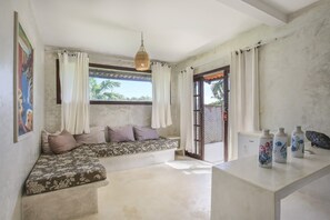 Quarto com sofá, mesa decorada com vasos e vista para o exterior.