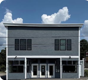 A two-story building with a flat roof, large windows, and a central entrance with a door.