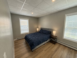 A bedroom with a bed, two bedside lamps, a window with blinds, and a ceiling with recessed lighting.