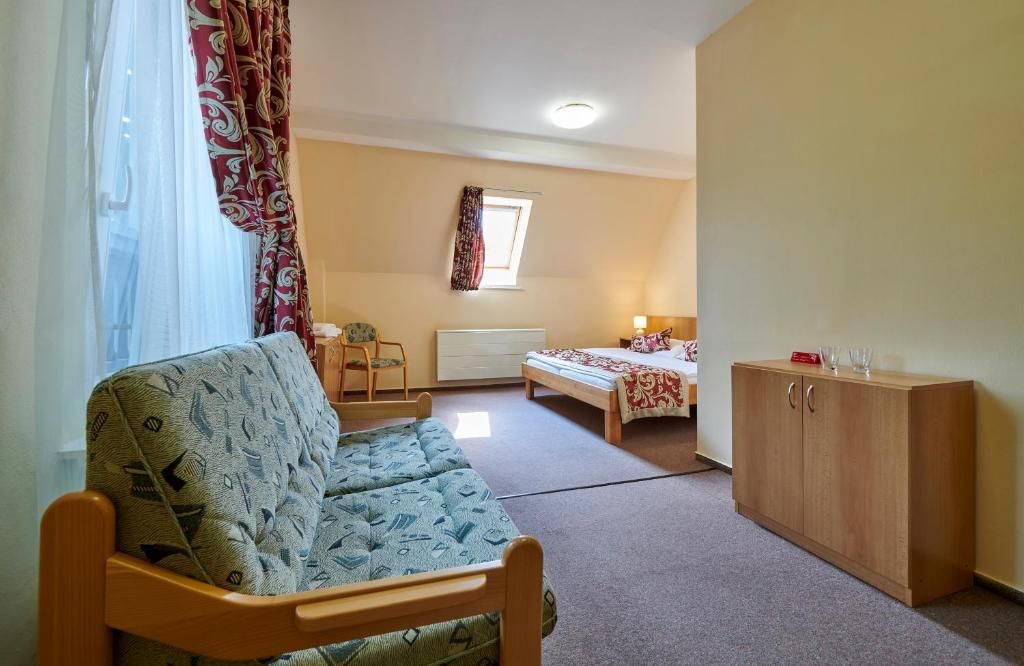 A compact room with a sofa, a bed, a small table, and a cabinet.
