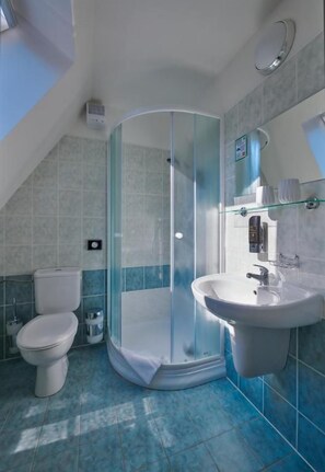 A bathroom with a glass-enclosed shower, a sink, and a toilet. - Hotel Mezní Louka (Hřensko)