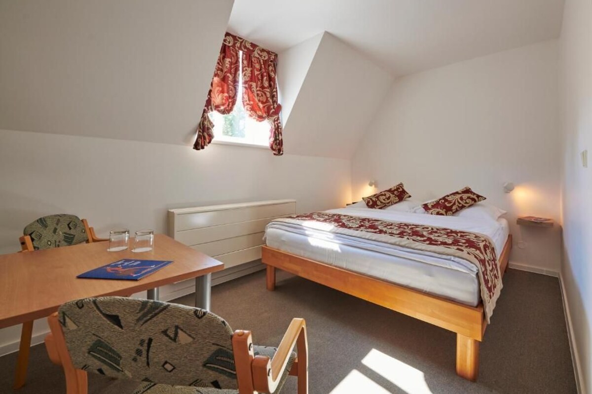 Um quarto com cama, mesa e cadeiras.