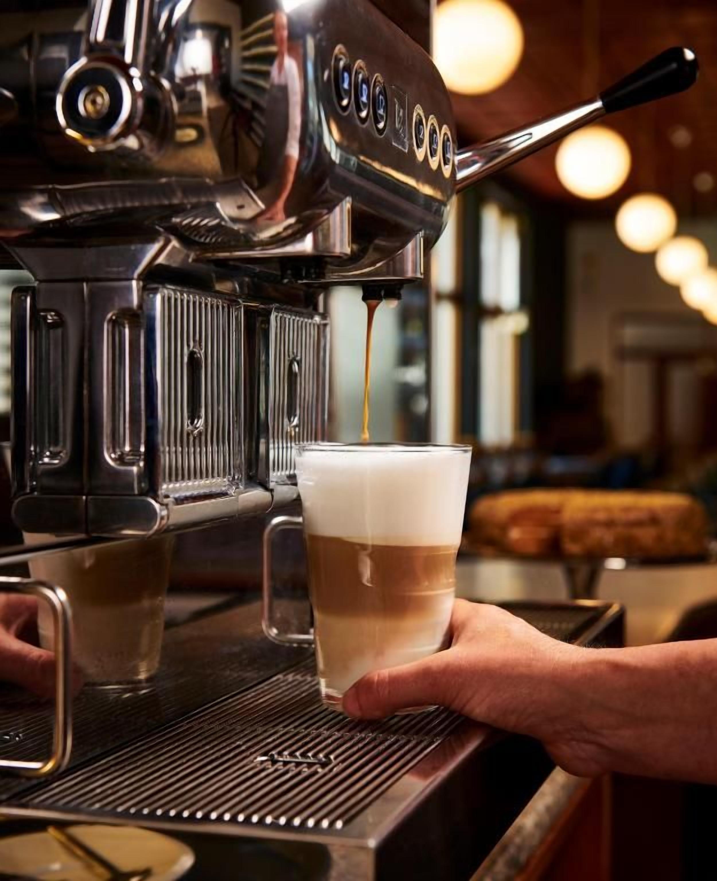 Um barista preparando uma bebida de café em uma máquina.