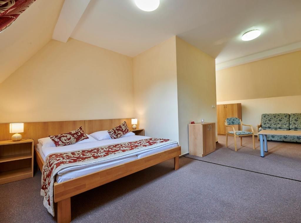 Ein Schlafzimmer mit einem hölzernen Bett, Nachttischen, einem Schrank, einer Couch und einem kleinen Tisch.