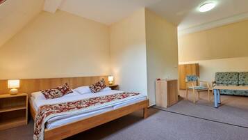 Ein Schlafzimmer mit einem hölzernen Bett, Nachttischen, einem Schrank, einer Couch und einem kleinen Tisch.