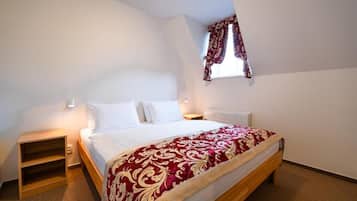 Ein Schlafzimmer mit einem Bett, Nachttischen, einem Fenster mit Vorhängen und einem Teppichboden.