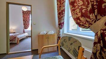 Quarto com cama, um armário de madeira, uma cadeira e janela com cortinas.