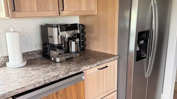 Eine Küche mit Holzschränken, einem Edelstahlkühlschrank, einer Kaffeemaschine und einem Geschirrspüler.