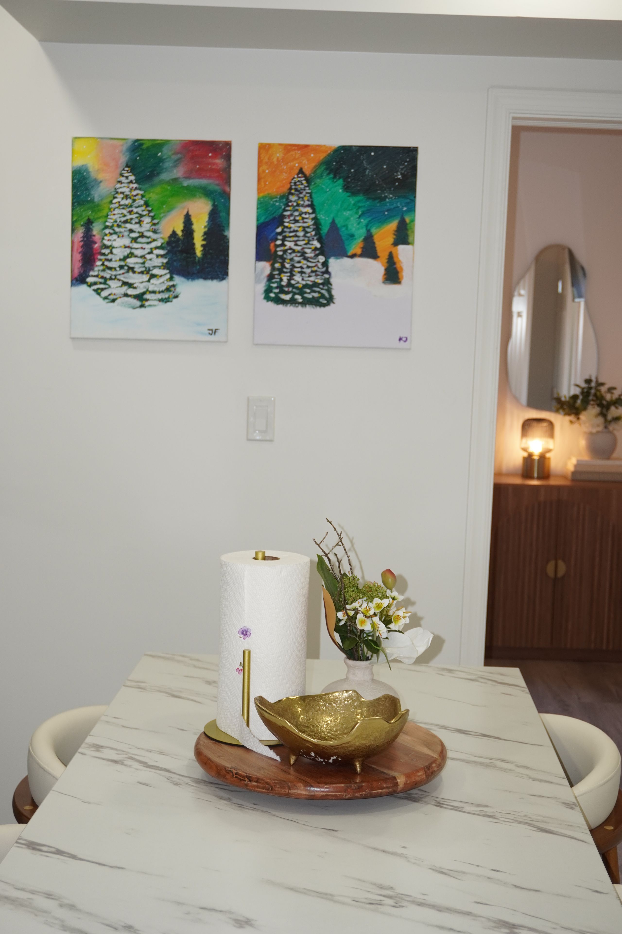 Un coin repas avec une table en marbre, un rouleau de papier toilette, un bol décoratif et un vase rempli de fleurs.