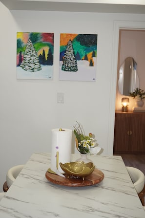 Un comedor con una mesa de mármol, un rollo de papel higiénico, un cuenco decorativo y un florero con flores.