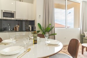 A modern dining area with a round table set for four, a bottle of wine, and a potted plant. - Cica Studio by Atlantic Holiday (Santa Cruz)