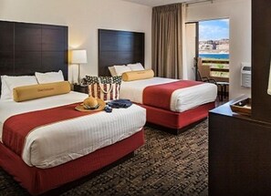 Ein Hotelzimmer mit zwei Betten, Meerblick und einem Balkon.