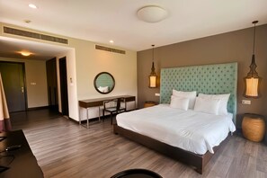 Una habitación de hotel con una cama grande, un escritorio, una silla y un espejo redondo.
