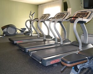 Vier StarTrac Laufbänder in einem Fitnessstudio mit Spiegelwand und einem fensterförmigen Bereich mit Vorhängen.
