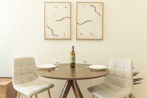 A dining table with two chairs, a bottle of wine, and two glasses. - Cravo Studio by Atlantic Holiday (Santa Cruz)