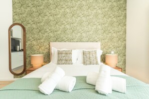 Una camera d'albergo con un letto, due lampade da comodino, uno specchio e una parete verde con texture.