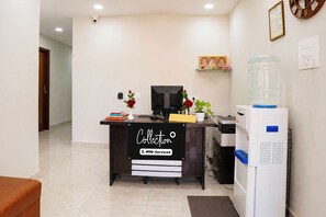 A reception desk with a sign reading 'Collection OYO-Serviced,' a water dispenser, a computer, and a plant.