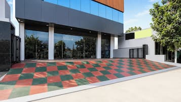 Un bâtiment moderne avec un sol à motifs de carreaux, de grandes fenêtres et un arbre en arrière-plan.