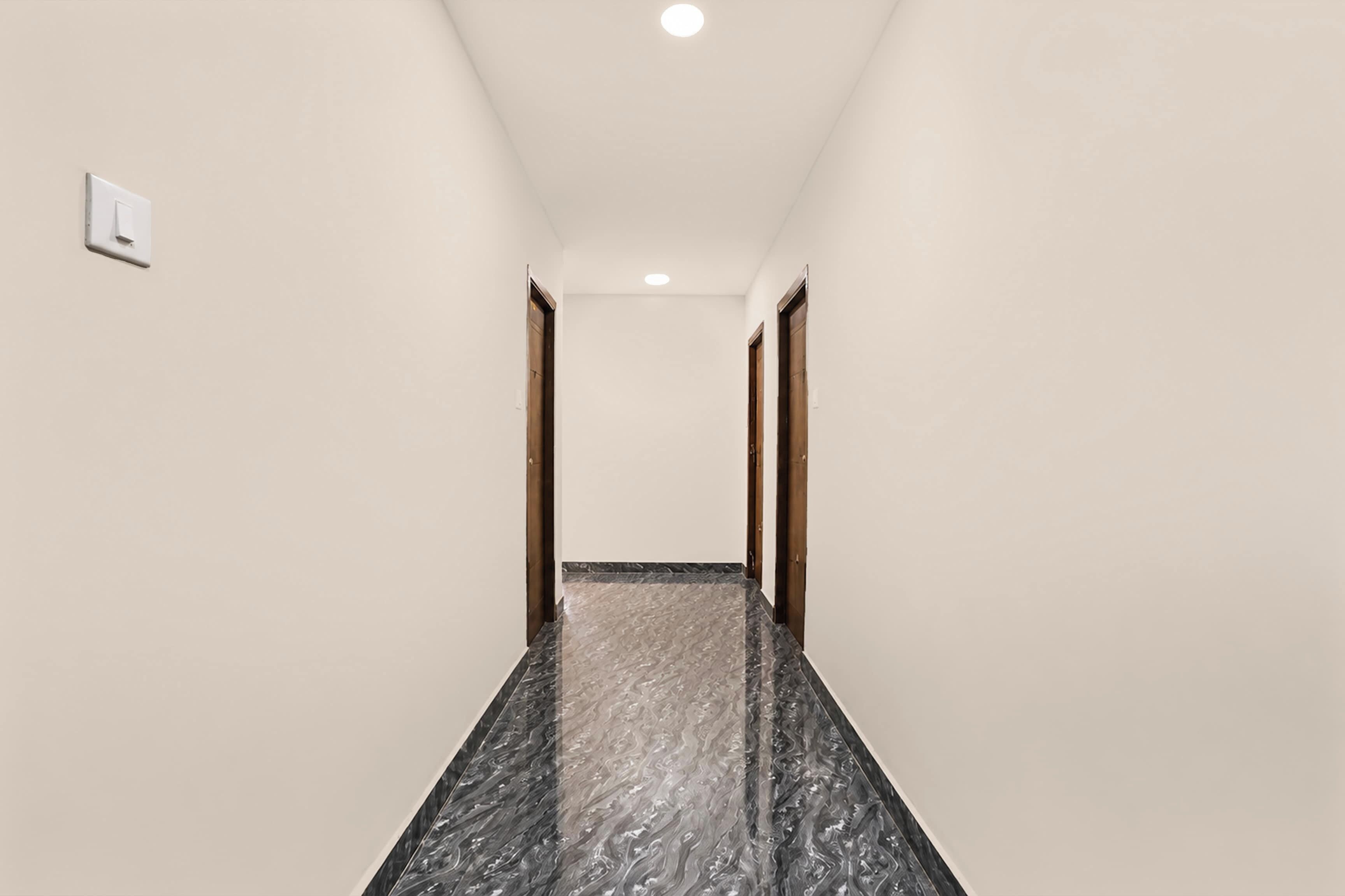 Un couloir doté d’un sol en marbre, de murs blancs et de portes en bois.