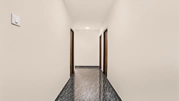 Un couloir doté d’un sol en marbre, de murs blancs et de portes en bois.