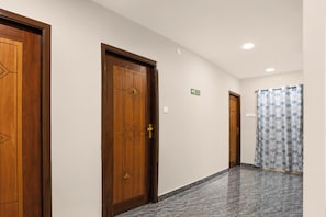 A hallway with wooden doors, a shower curtain, and a sign indicating a bathroom. - Super Collection O Vedayapalem Railway (Nellore)