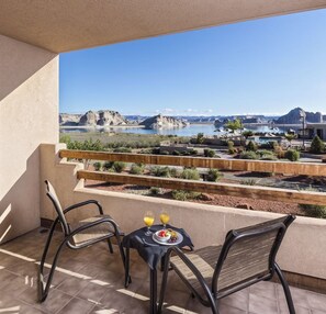 Ein Balkon mit zwei Stühlen und einem Tisch, der auf eine malerische Landschaft mit Felsformationen und einem Gewässer blickt.