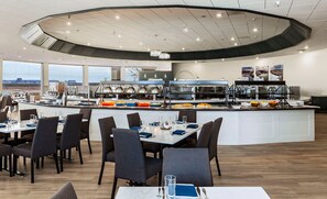 Ein moderner Essbereich mit einem zentralen Buffet und mehreren Tischen mit Stühlen.