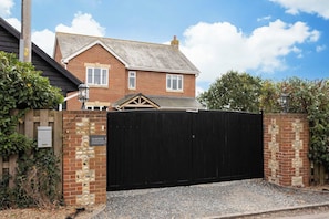 A residential property with a brick house, a black metal gate, and a gravel driveway. - Spacious Sidlesham Country Home near Witterings (Sidlesham)