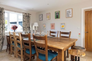 A dining room with a wooden table and chairs, a vase of flowers, and various framed pictures on the wall. - Spacious Sidlesham Country Home near Witterings (Sidlesham)