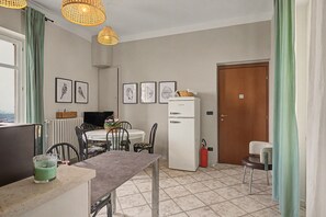 A compact kitchen with a dining table, chairs, a refrigerator, and a television.