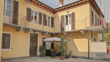 Ein zweistöckiges Gebäude mit Balkon, Tür und Topfpflanzen.