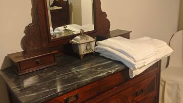 A wooden dresser with a mirror, a small decorative box, and a stack of white towels.