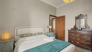 A neatly made bed with a headboard, a bedside lamp, a dresser with drawers, and a mirror.