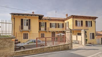 A two-story building with a yellow facade, multiple windows with shutters, and a gated entrance.