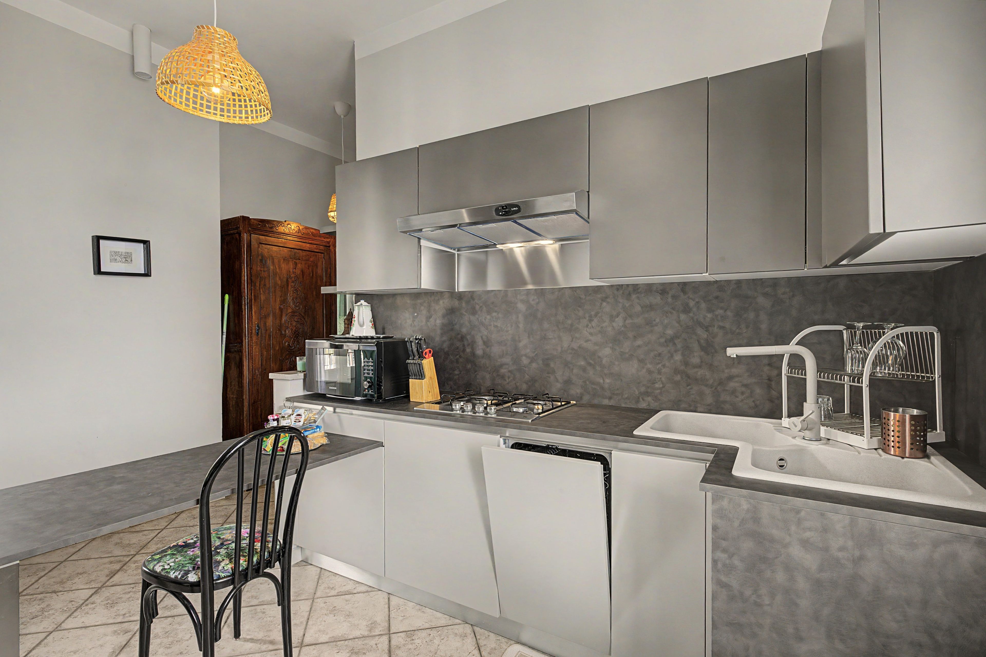 A modern kitchen with a central island, stainless steel appliances, and a hanging light fixture.
