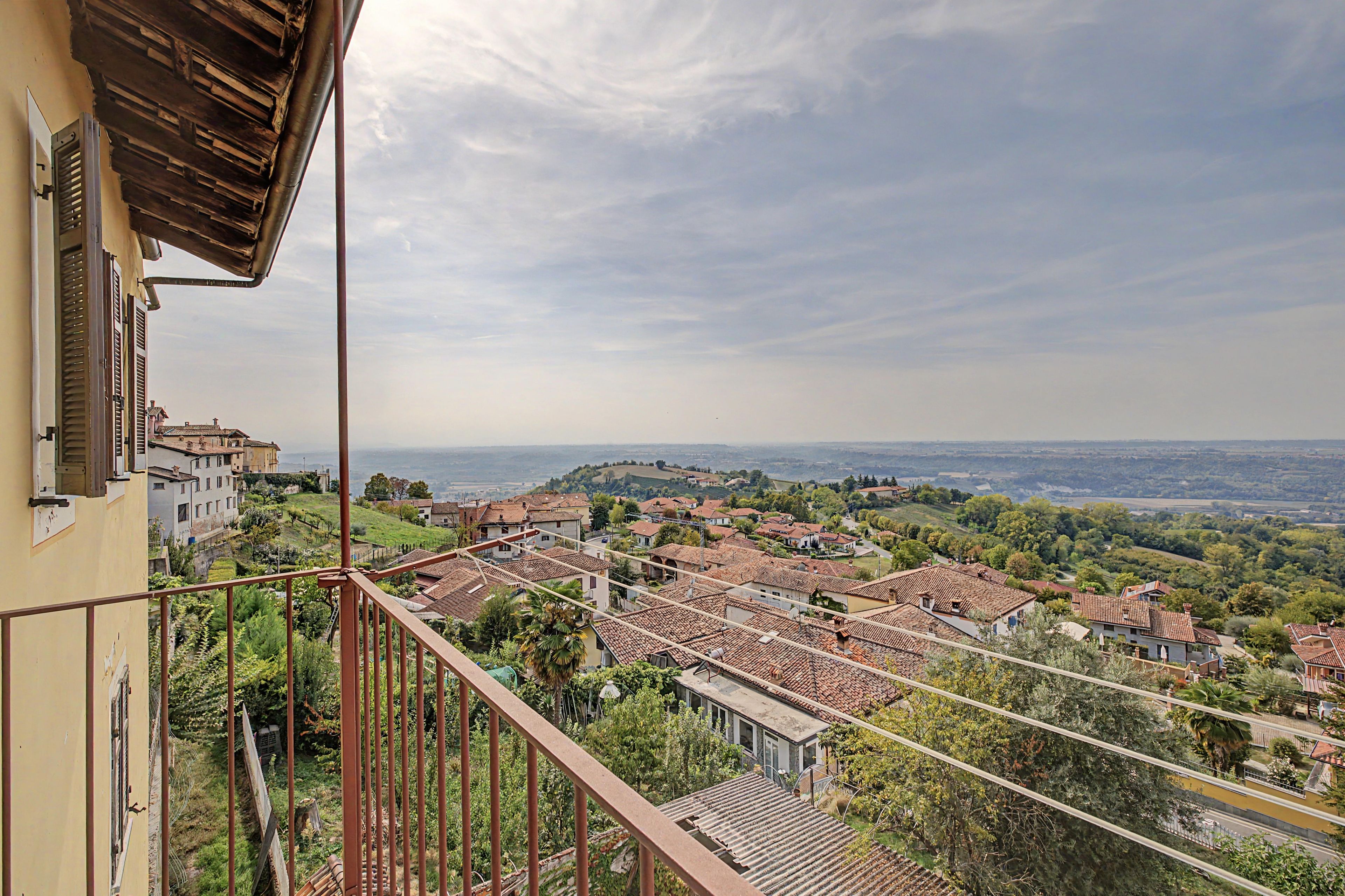 A balcony with a view of a village and distant hills.