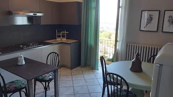 Een kleine keuken met een gasfornuis, een spoelbak en een eethoek met stoelen en een tafel.