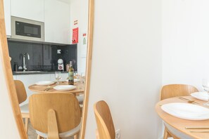Cozinha moderna com micro-ondas, pia e garrafa de vinho no balcão.
