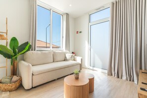 Uma sala de estar moderna com sofá, mesa de centro, planta e vista para o exterior.