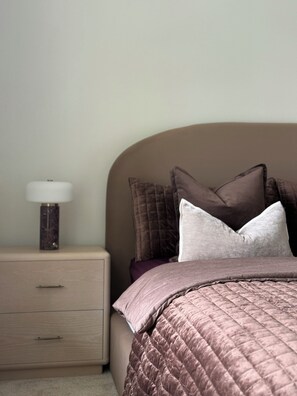 Un dormitorio con cama, mesita de noche y lámpara.