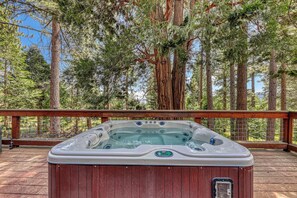 Ein Whirlpool auf einer Holzterrasse mit Blick auf hohe Kiefern im Hintergrund.