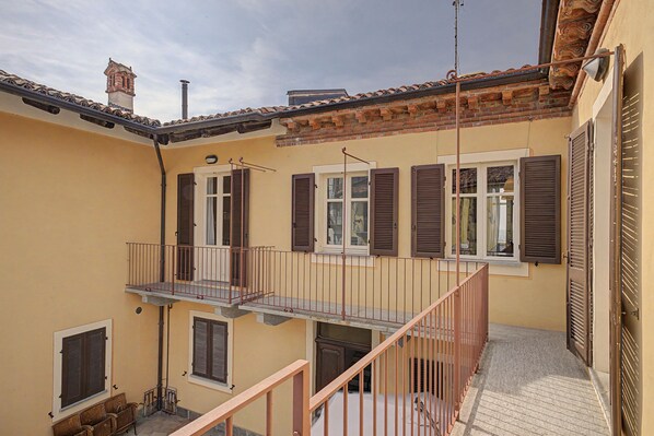 A residential building with a balcony, a staircase, and multiple windows with shutters.