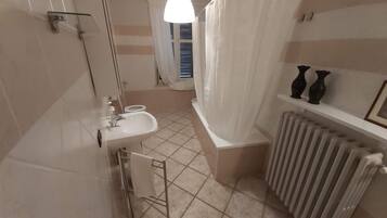 A bathroom with a sink, toilet, shower, and radiator.