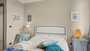Un dormitorio con cama, mesitas de noche, lámpara y decoración en la pared.