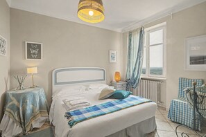 A bedroom with a bed, bedside tables, a lamp, a window with curtains, and a view of the outdoors.